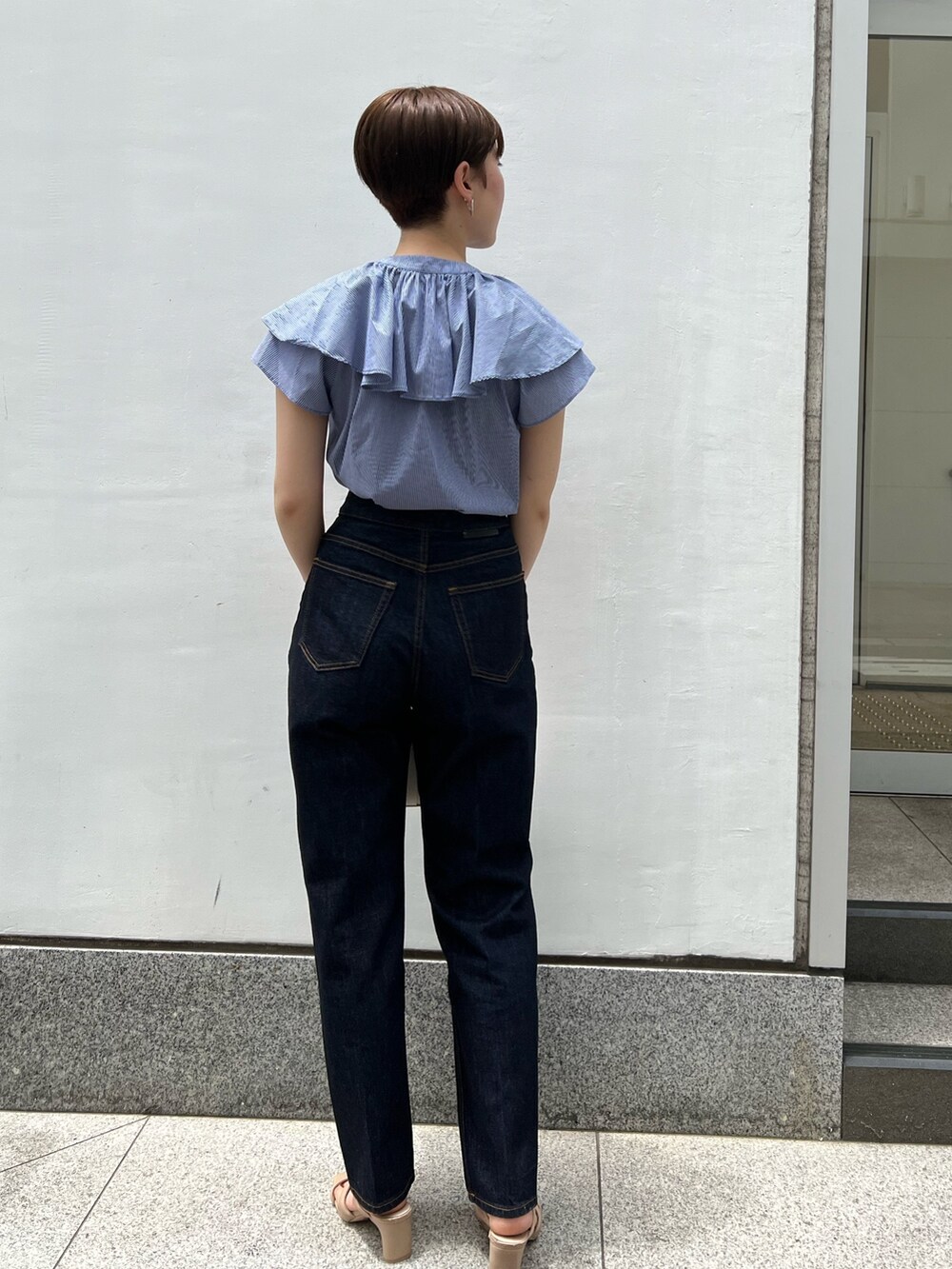 ベージュ系のサンダル、ホワイト系のショルダーバッグ、ブルー系のデニムパンツを着用したレディースの夏コーディネートの2枚目の写真