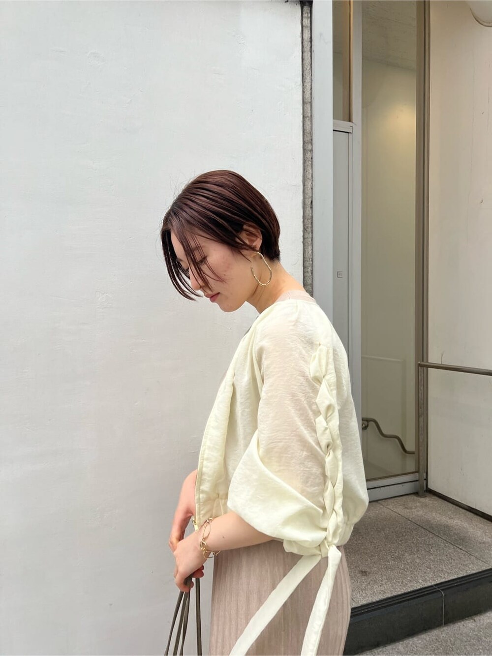 ベージュ系のハンドバッグ、ホワイト系のブルゾン、ベージュ系のワンピースを着用したレディースの春コーディネートの6枚目の写真