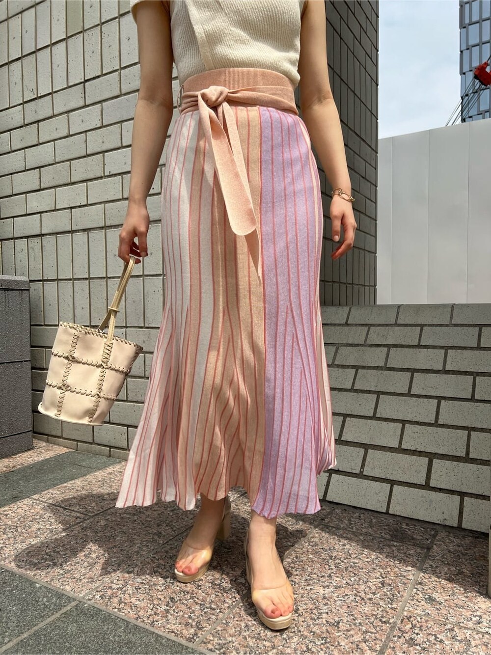 オレンジ系のスカート、その他のパンプス、ホワイト系のショルダーバッグを着用したレディースの春コーディネートの5枚目の写真