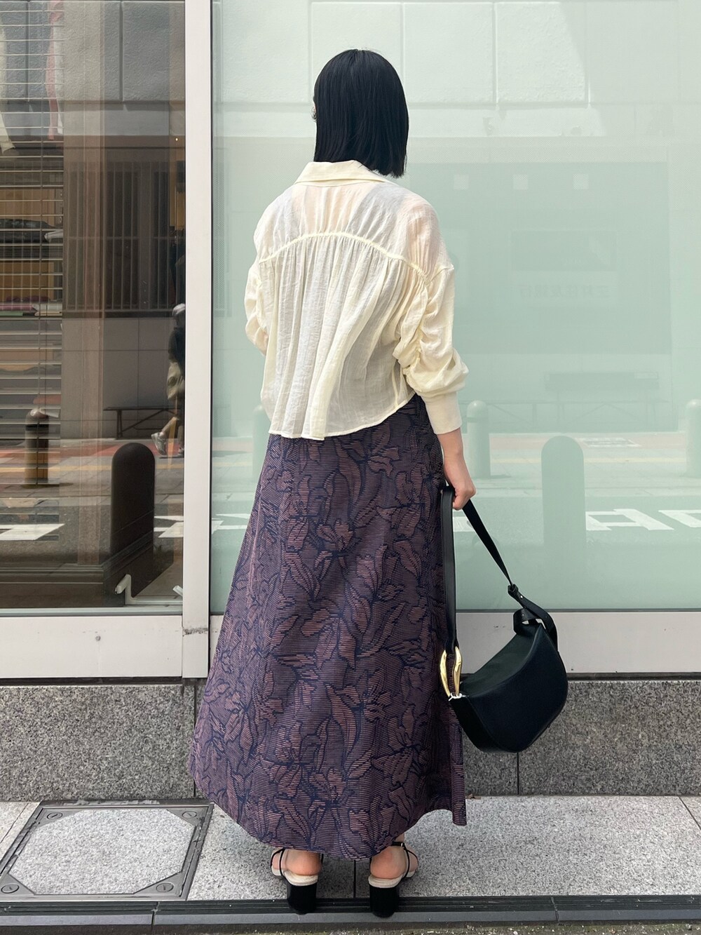 ブラック系のサンダル、ブラック系のワンピース、ホワイト系のシャツ/ブラウスを着用したレディースの春コーディネートの2枚目の写真