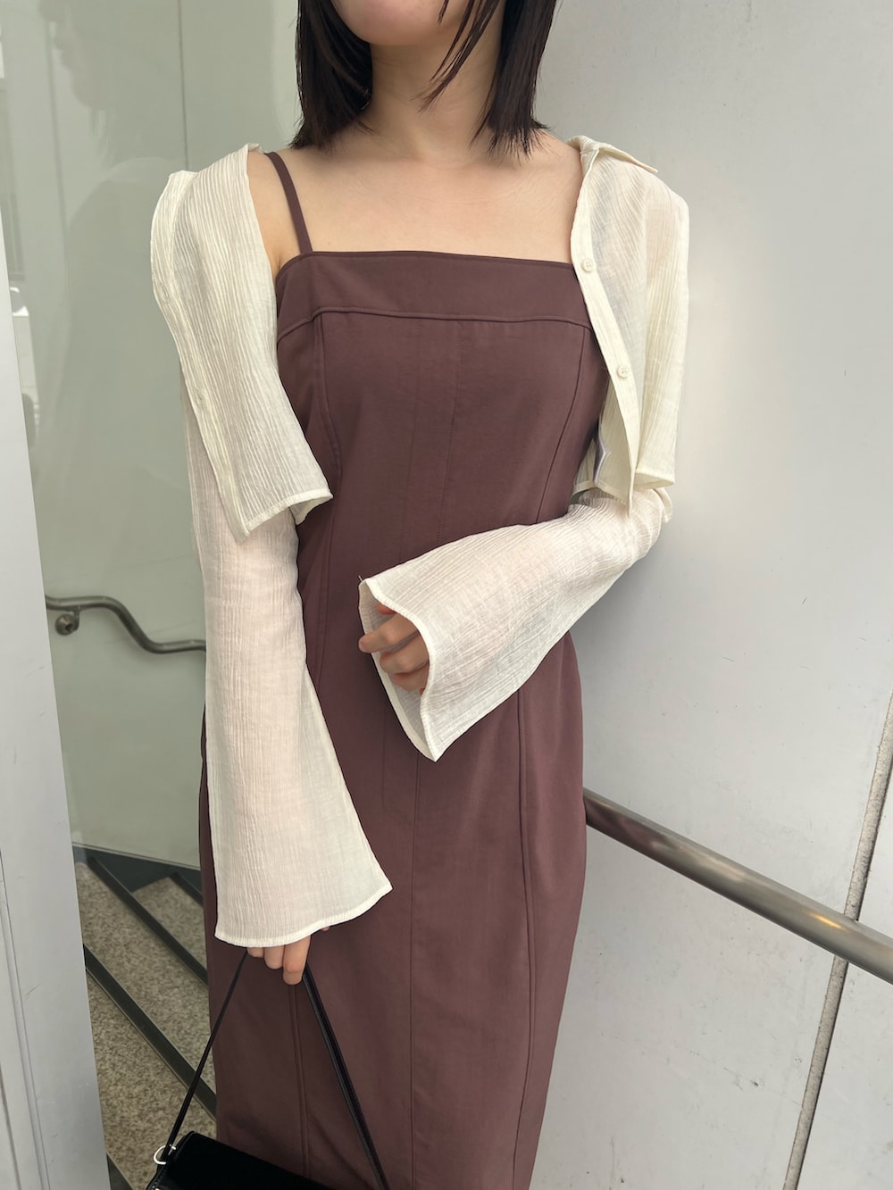 ブラック系のショルダーバッグ、ブラウン系のワンピース、ブラック系のブーツを着用したレディースの秋コーディネートの4枚目の写真