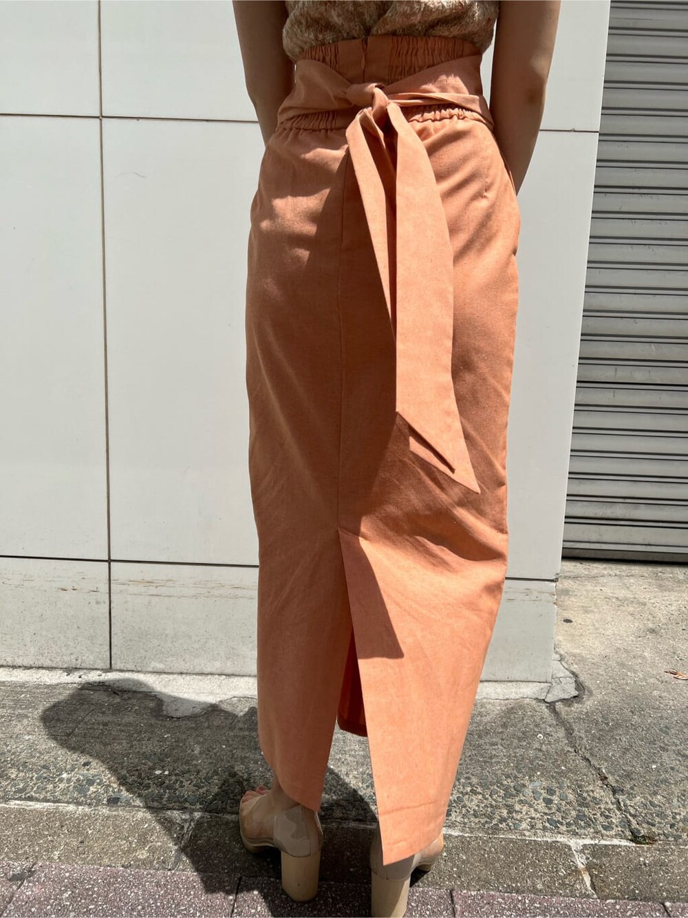 ホワイト系のハンドバッグ、オレンジ系のスカート、その他のパンプスを着用したレディースの春コーディネートの10枚目の写真