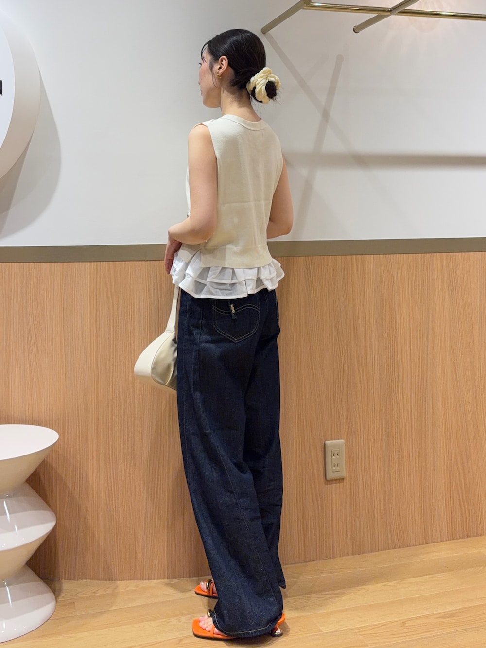ホワイト系のニット/セーター、オレンジ系のサンダル、ブルー系のデニムパンツを着用したレディースの夏コーディネートの2枚目の写真