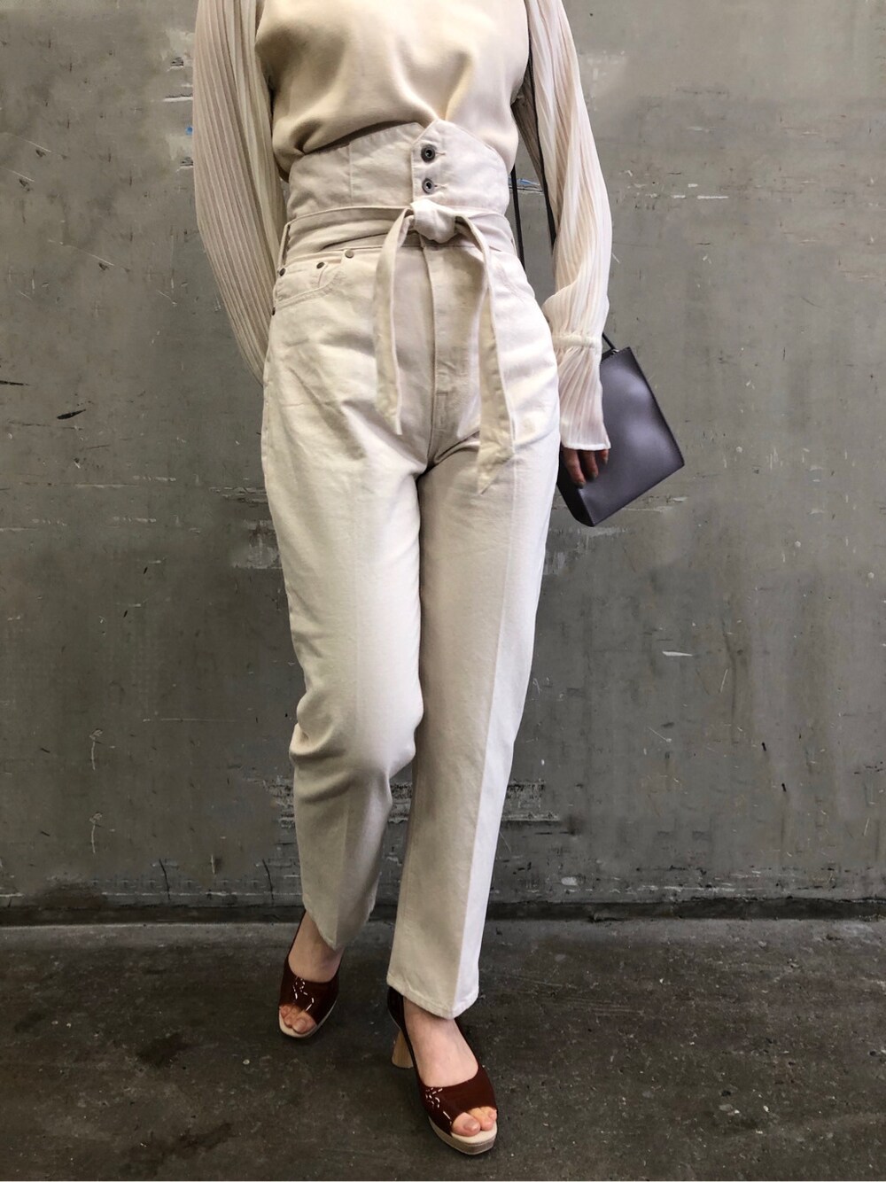 ブラウン系のパンプス、パープル系のハンドバッグ、ホワイト系のニット/セーターを着用したレディースの冬コーディネートの3枚目の写真