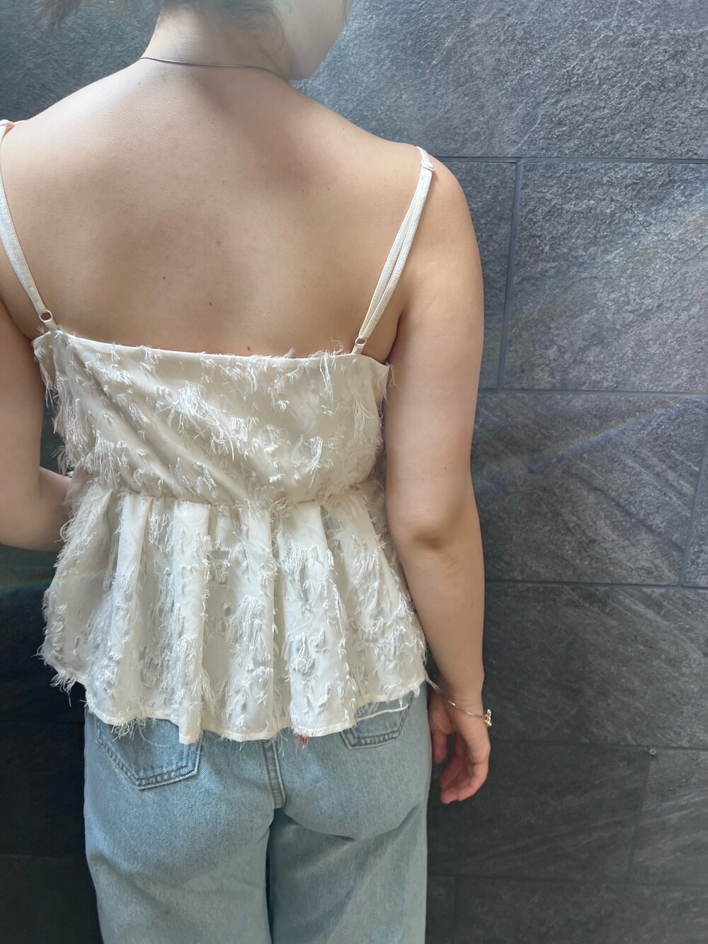 ホワイト系のサンダル、ホワイト系のキャミソール、ブルー系のデニムパンツを着用したレディースの夏コーディネートの4枚目の写真