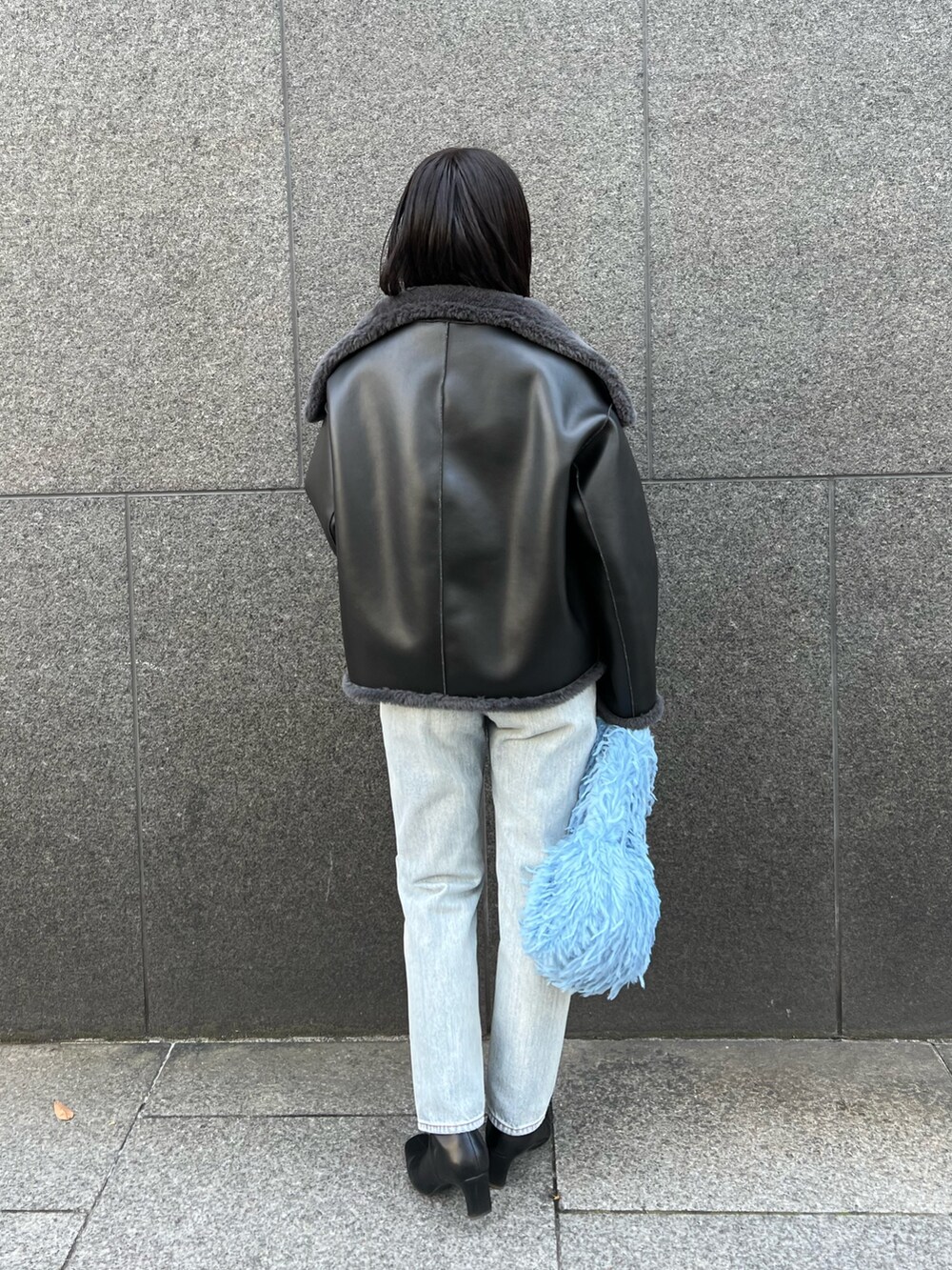 グレー系のムートンコート、ブルー系のデニムパンツを着用したレディースの冬コーディネートの2枚目の写真