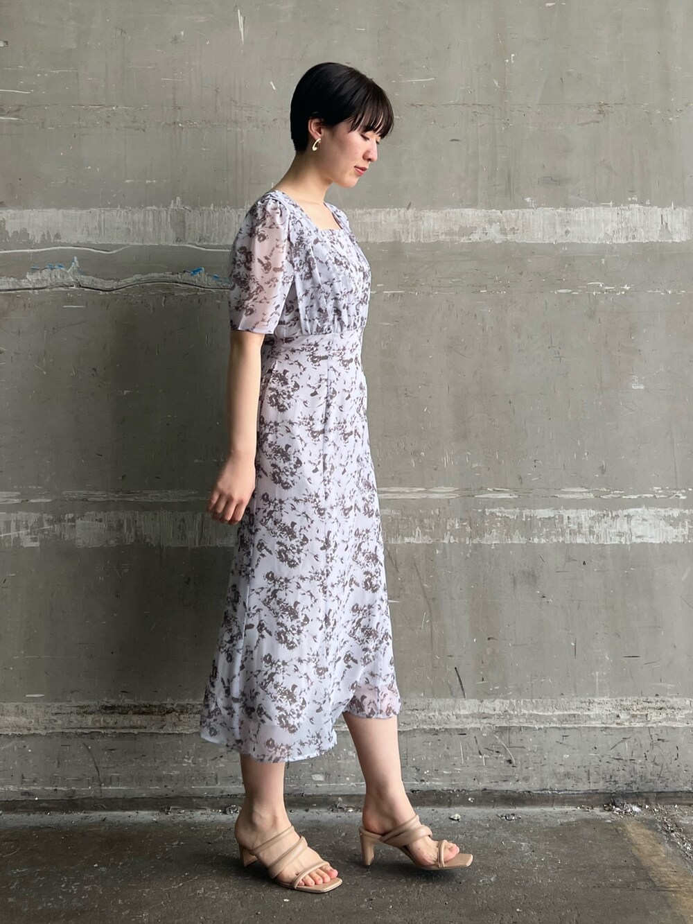 ベージュ系のサンダル、パープル系のワンピース、ホワイト系のハンドバッグを着用したレディースの春コーディネートの2枚目の写真