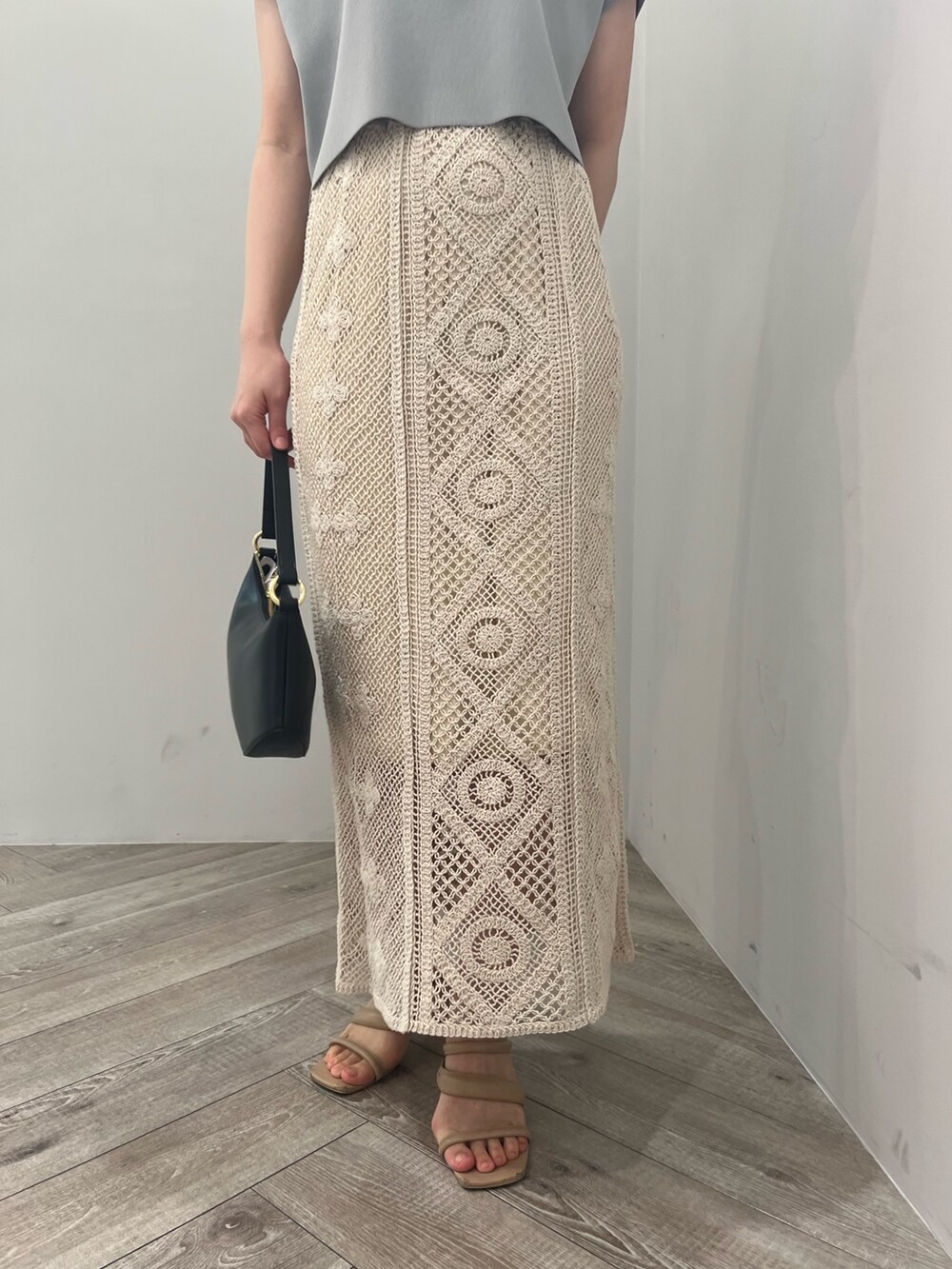 ベージュ系のサンダル、ブラック系のハンドバッグ、ブルー系のニット/セーターを着用したレディースの春コーディネートの6枚目の写真