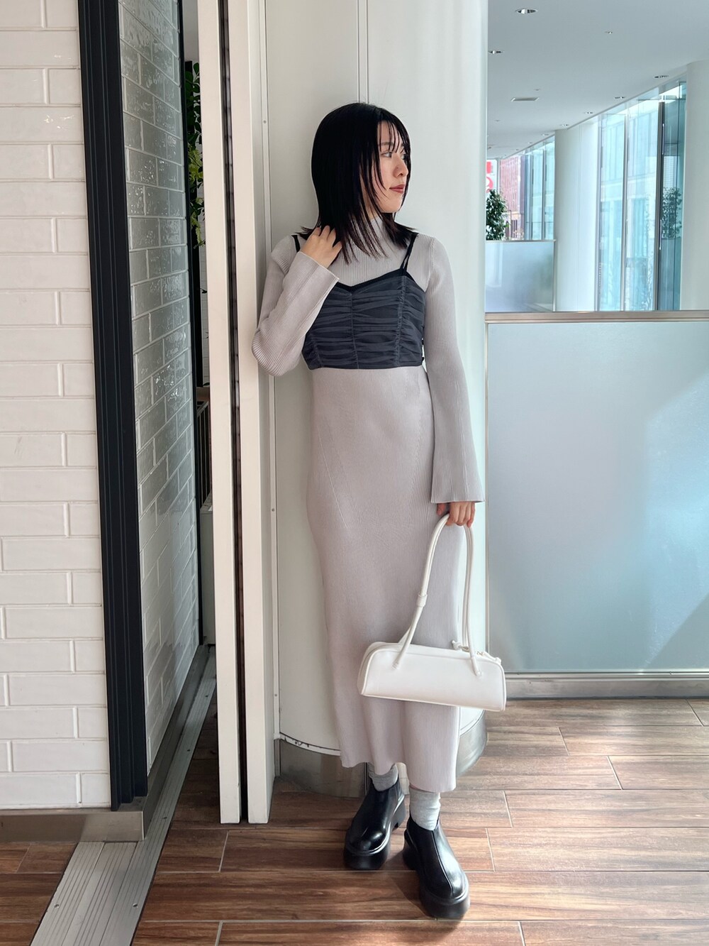 ブラック系のステンカラーコート、ブルー系のワンピース、ブラック系のブーツを着用したレディースの冬コーディネートの9枚目の写真