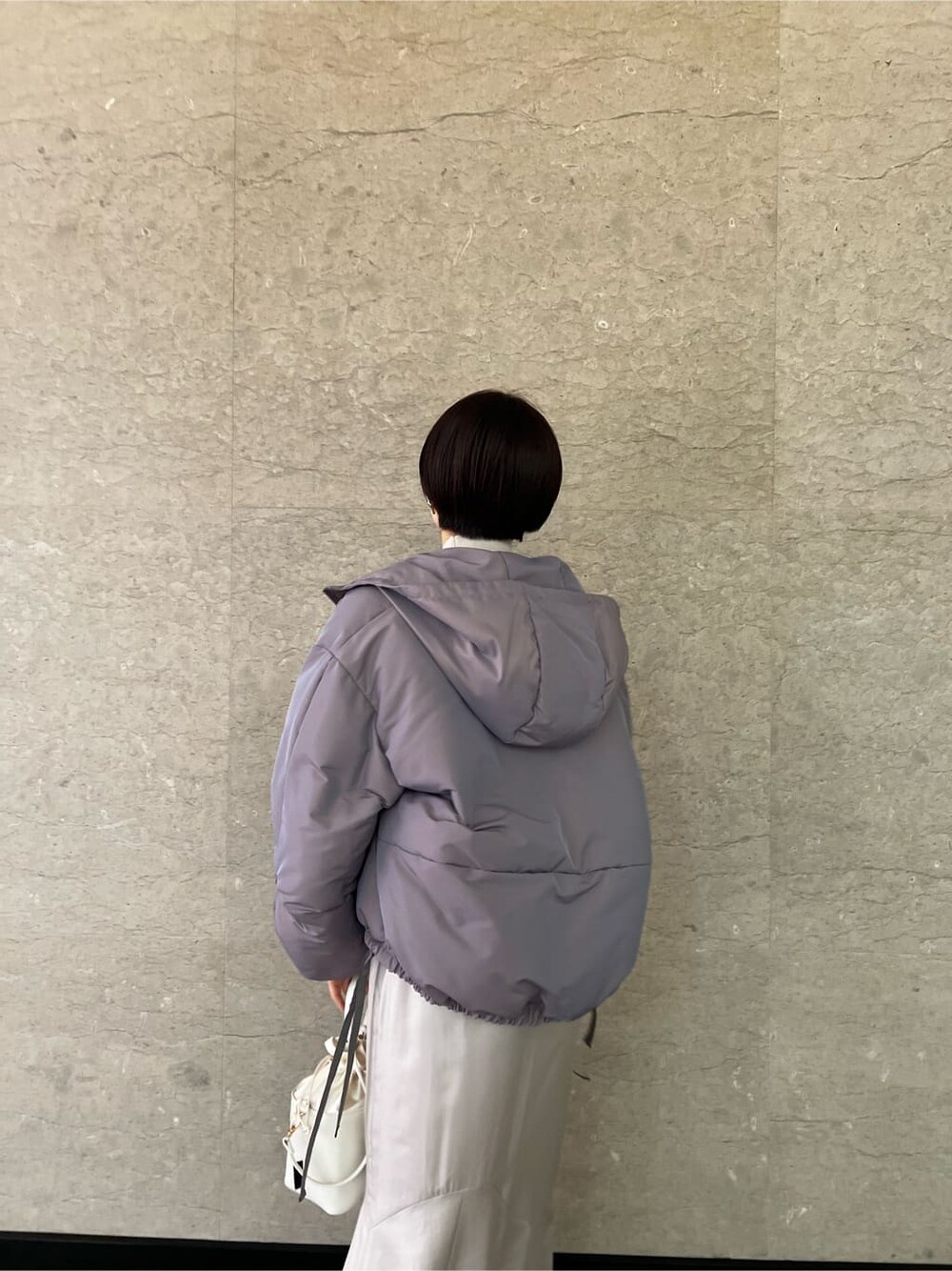 グレー系のスカート、パープル系のその他アウター、ホワイト系のハンドバッグを着用したレディースの冬コーディネートの3枚目の写真