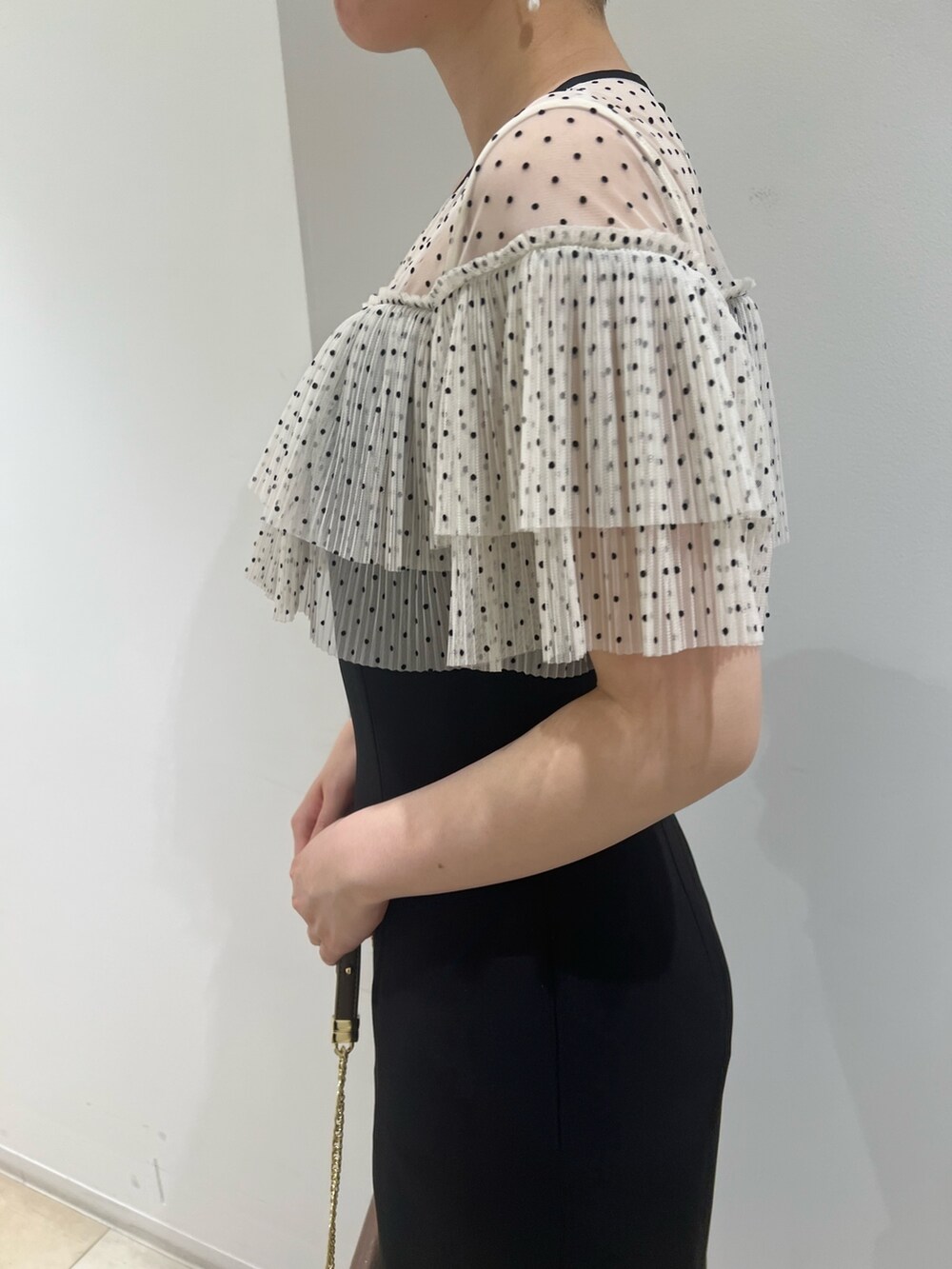 ゴールド系のパンプス、ゴールド系のハンドバッグ、ブラック系のドレスを着用したレディースの夏コーディネートの5枚目の写真