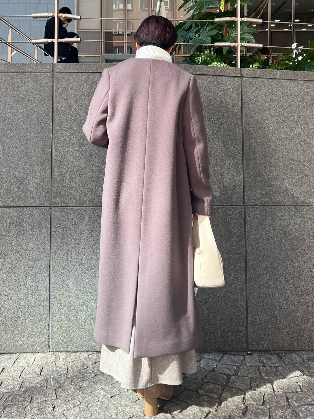 ベージュ系のブーツ、グレー系のスカート、ホワイト系のハンドバッグを着用したレディースの秋コーディネートの2枚目の写真