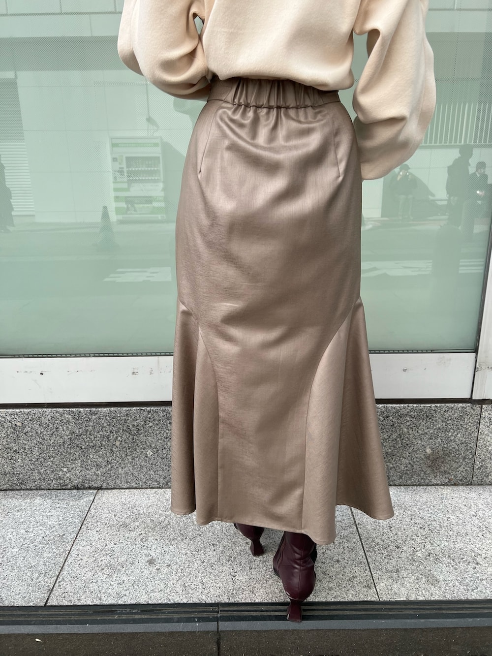 レッド系のブーツ、ベージュ系のスカート、ホワイト系のニット/セーターを着用したレディースの冬コーディネートの8枚目の写真