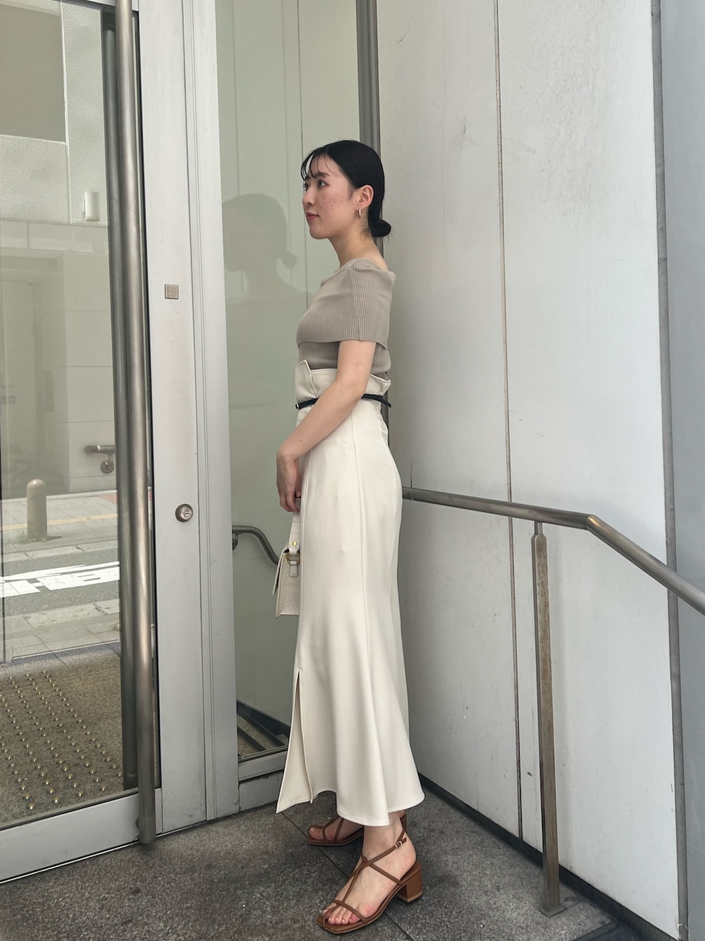 ホワイト系のショルダーバッグ、ホワイト系のスカート、ベージュ系のニット/セーターを着用したレディースの夏コーディネートの2枚目の写真