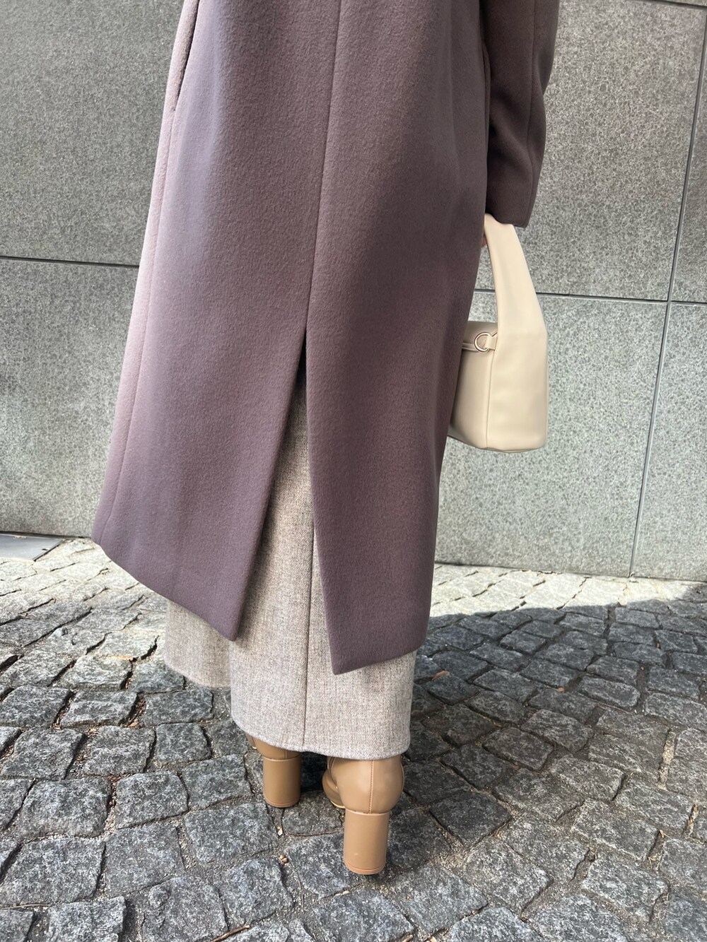 ベージュ系のブーツ、グレー系のスカート、ホワイト系のハンドバッグを着用したレディースの秋コーディネートの3枚目の写真