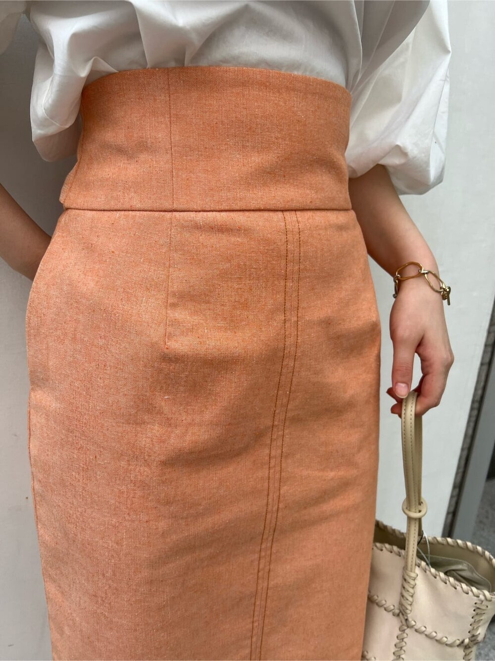 ホワイト系のシャツ/ブラウス、オレンジ系のスカート、ブラウン系のパンプスを着用したレディースの春コーディネートの8枚目の写真