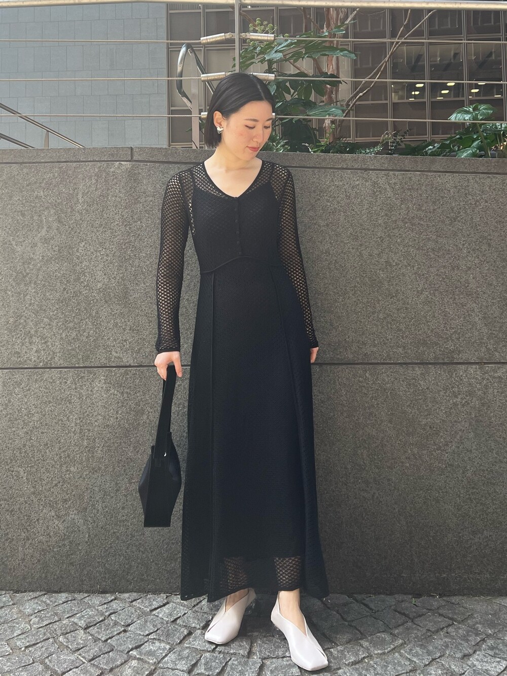 ブラック系のデニムジャケット、ホワイト系のパンプス、ブラック系のハンドバッグを着用したレディースの春コーディネートの4枚目の写真