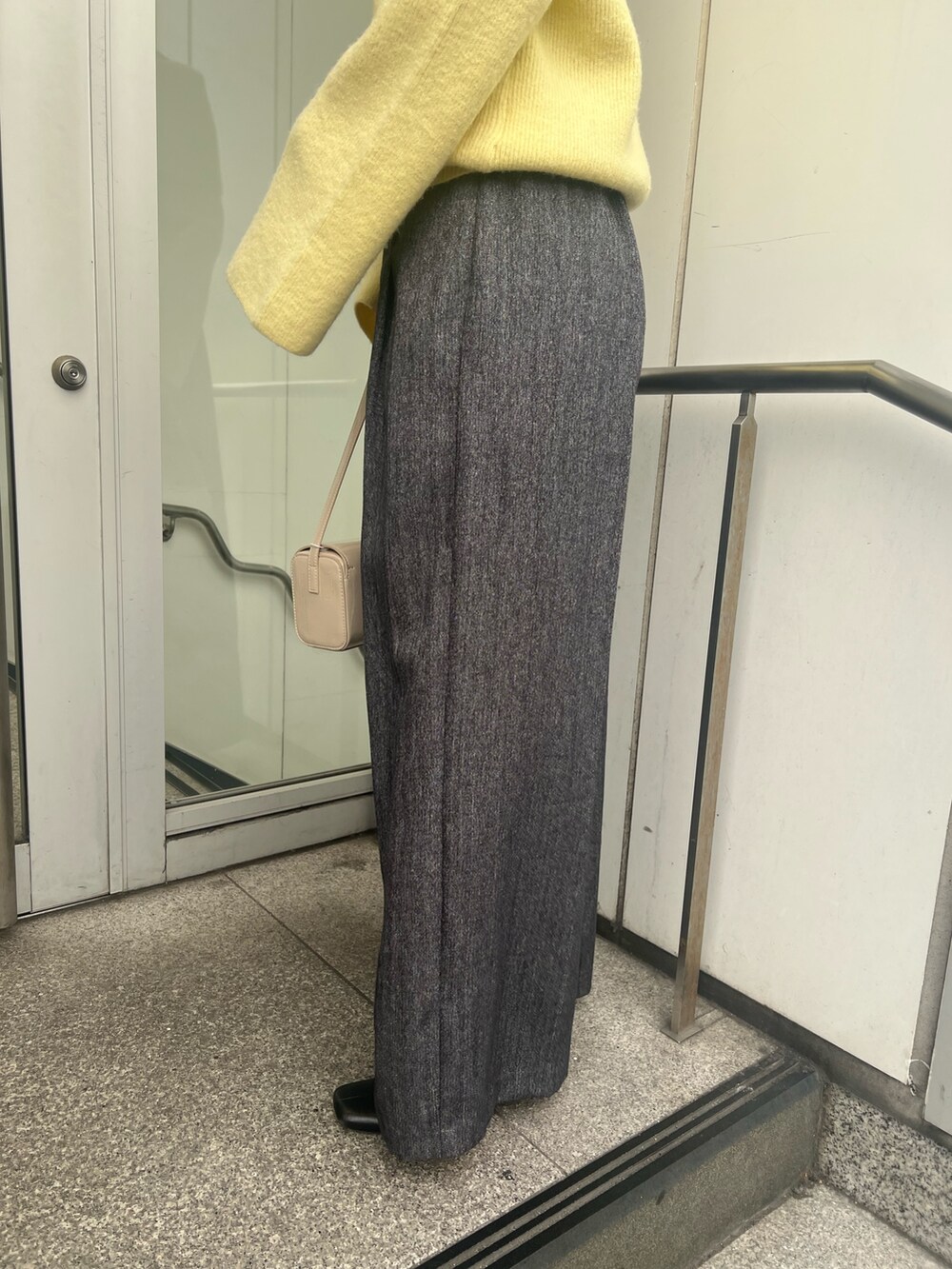 イエロー系のニット/セーター、ブラック系のブーツ、グレー系のその他パンツを着用したレディースの冬コーディネートの7枚目の写真