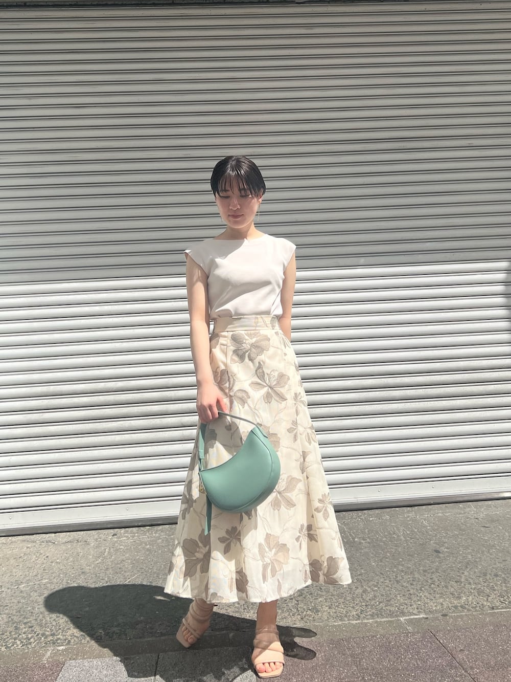 グリーン系のハンドバッグ、ホワイト系のニット/セーター、ベージュ系のサンダルを着用したレディースの春コーディネートの6枚目の写真