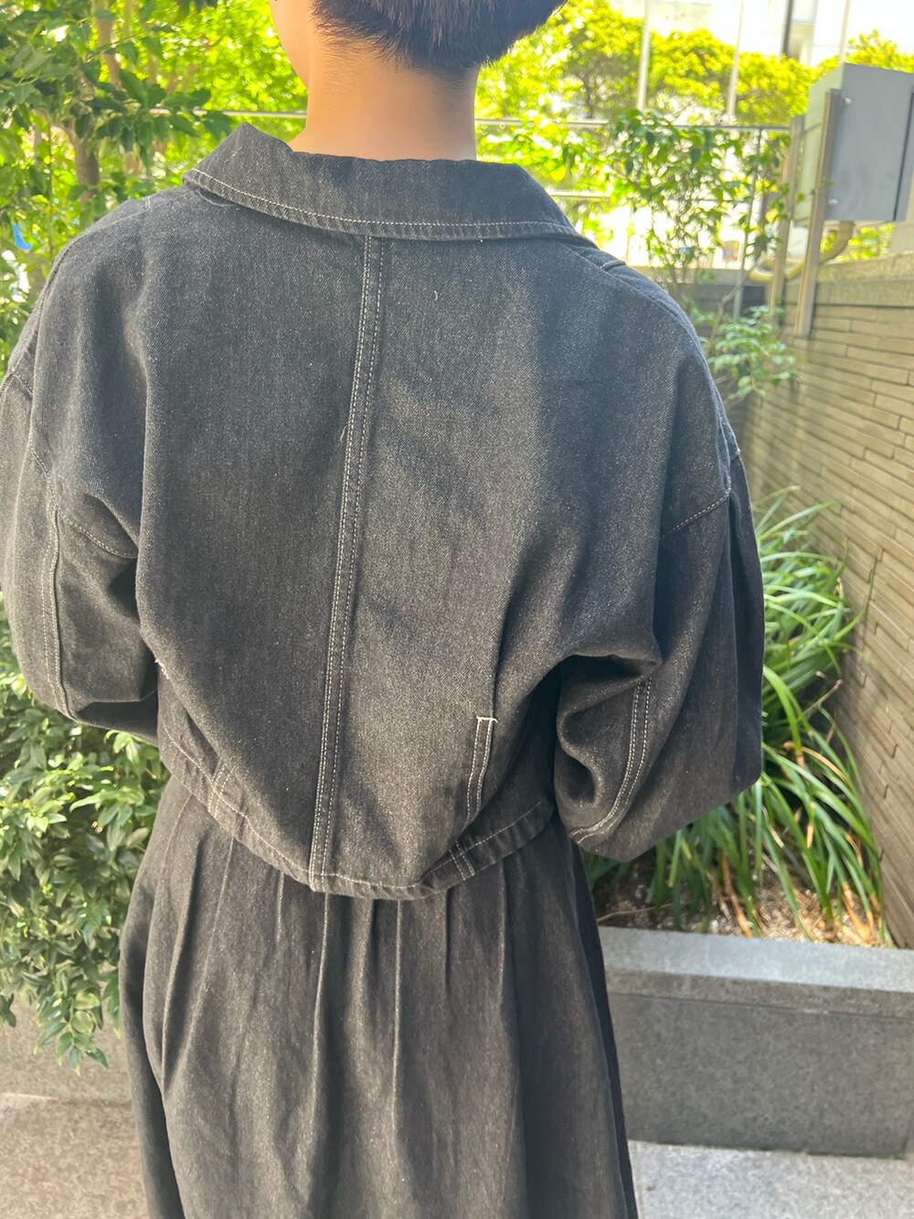 ブラック系のデニムジャケット、ブルー系のニット/セーター、ホワイト系のハンドバッグを着用したレディースの秋コーディネートの5枚目の写真