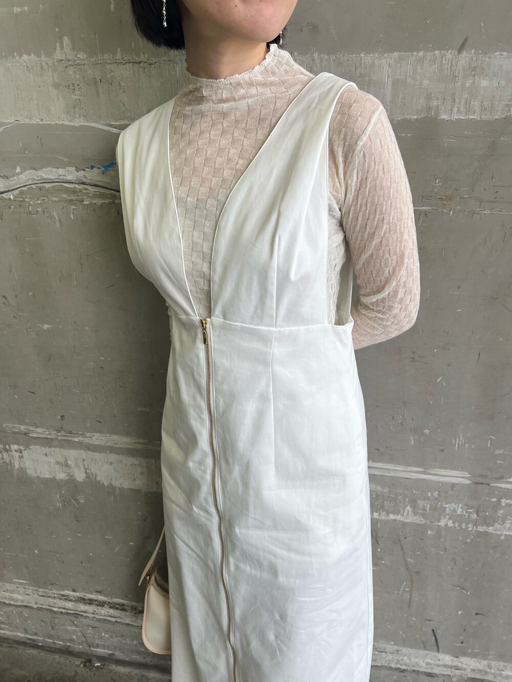 ホワイト系のジャンパースカート、ベージュ系のハンドバッグ、ホワイト系のTシャツ/カットソーを着用したレディースの春コーディネートの3枚目の写真