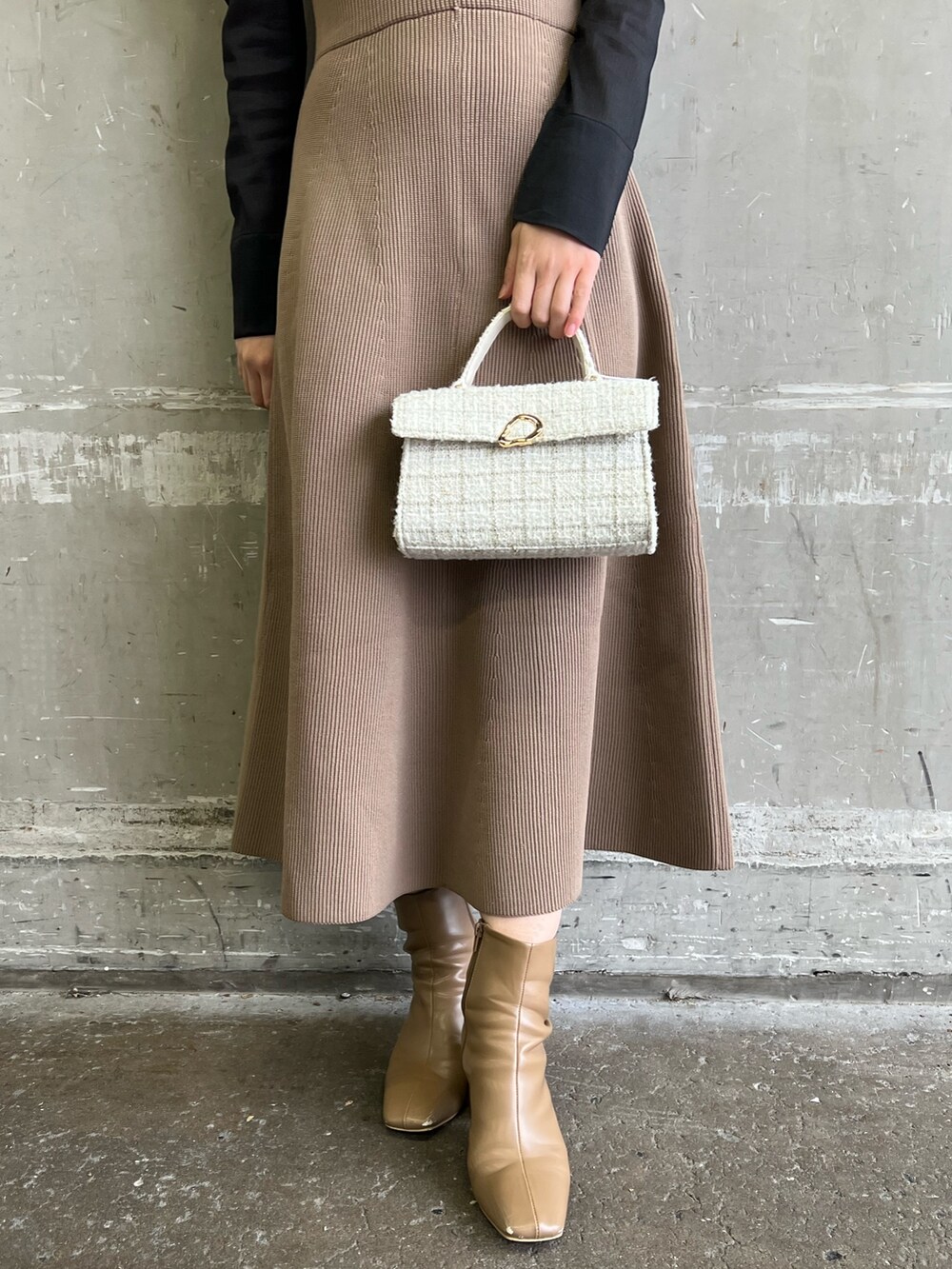 ブラック系のニット/セーター、ホワイト系のショルダーバッグ、ベージュ系のブーツを着用したレディースの冬コーディネートの6枚目の写真