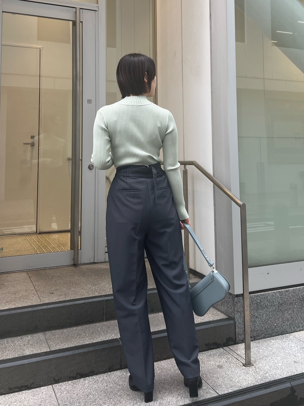 ブルー系のショルダーバッグ、グレー系のスラックス、グリーン系のニット/セーターを着用したレディースの冬コーディネートの3枚目の写真