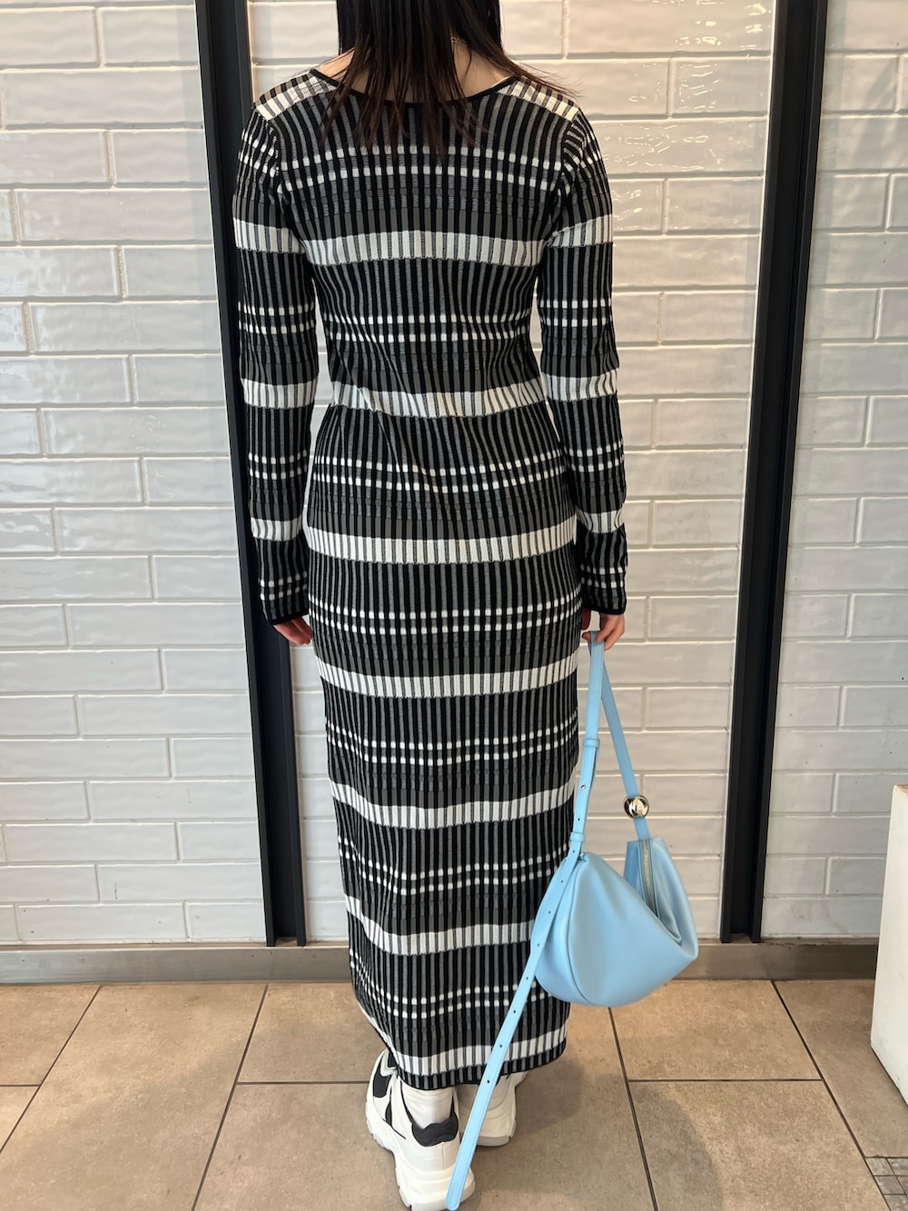 ブルー系のショルダーバッグ、ブラック系のワンピース、グレー系のスニーカーを着用したレディースの冬コーディネートの8枚目の写真