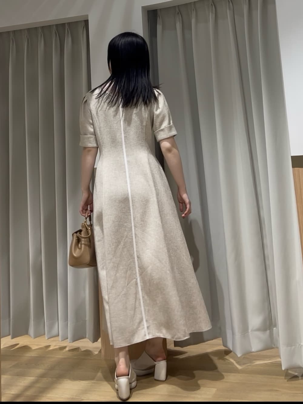 イエロー系のハンドバッグ、ベージュ系のワンピースを着用したレディースの春コーディネートの3枚目の写真