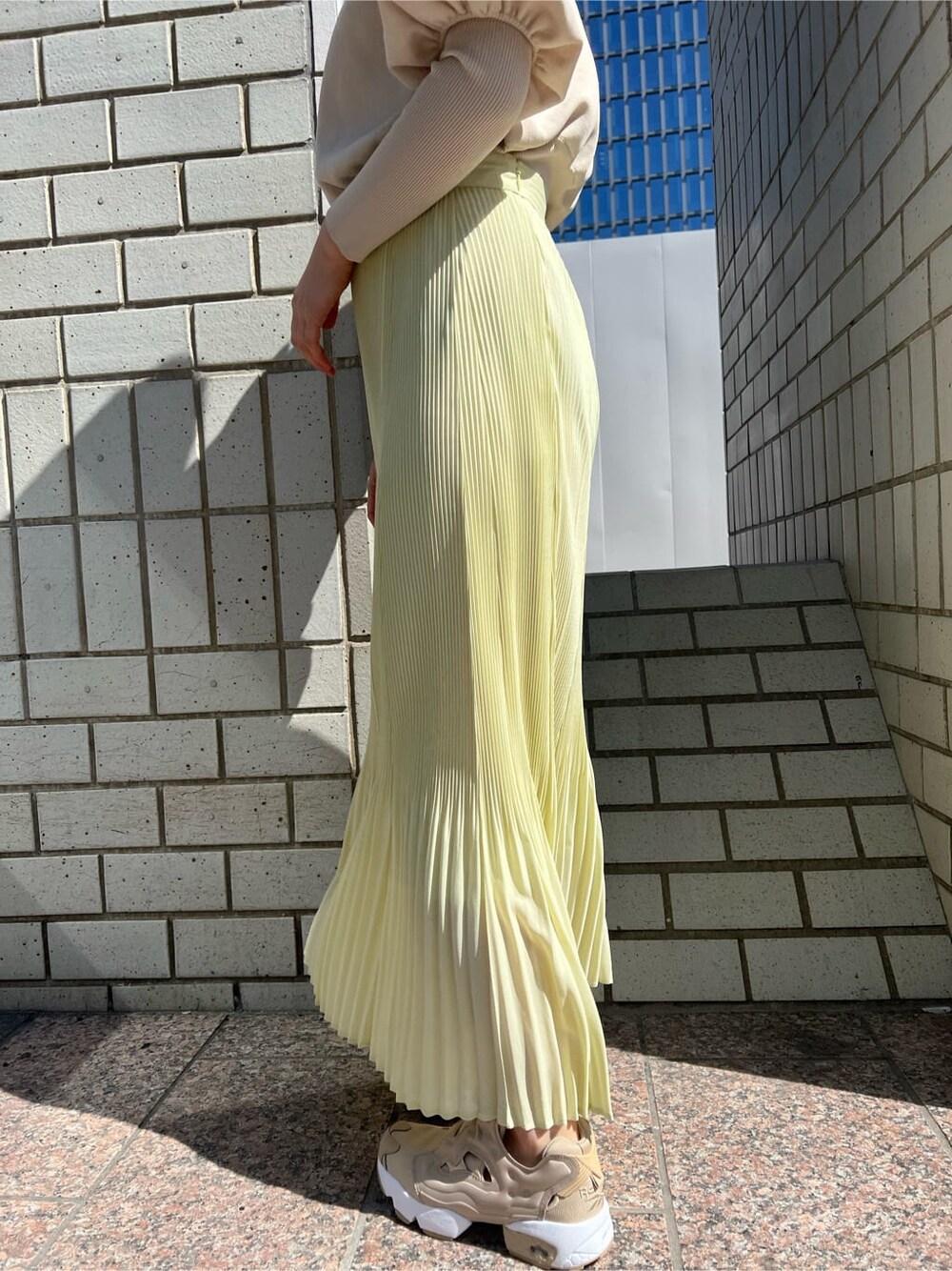 ブルー系のブルゾン、イエロー系のスカート、ベージュ系のニット/セーターを着用したレディースの春コーディネートの9枚目の写真