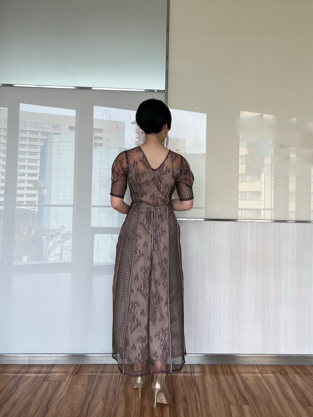 ゴールド系のハンドバッグ、ゴールド系のパンプス、ベージュ系のドレスを着用したレディースの冬コーディネートの2枚目の写真