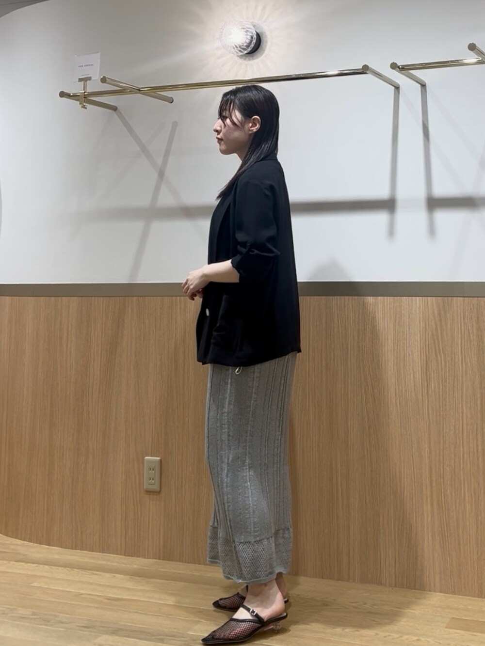 グリーン系のワンピース、ブラック系のテーラードジャケットを着用したレディースの夏コーディネートの2枚目の写真