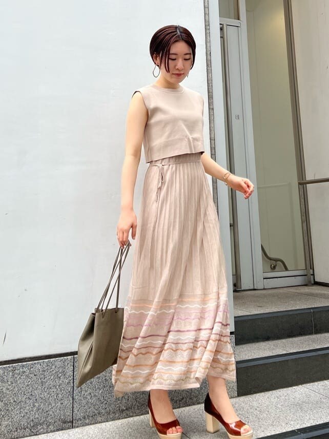 ベージュ系のハンドバッグ、ホワイト系のブルゾン、ベージュ系のワンピースを着用したレディースの春コーディネートの4枚目の写真