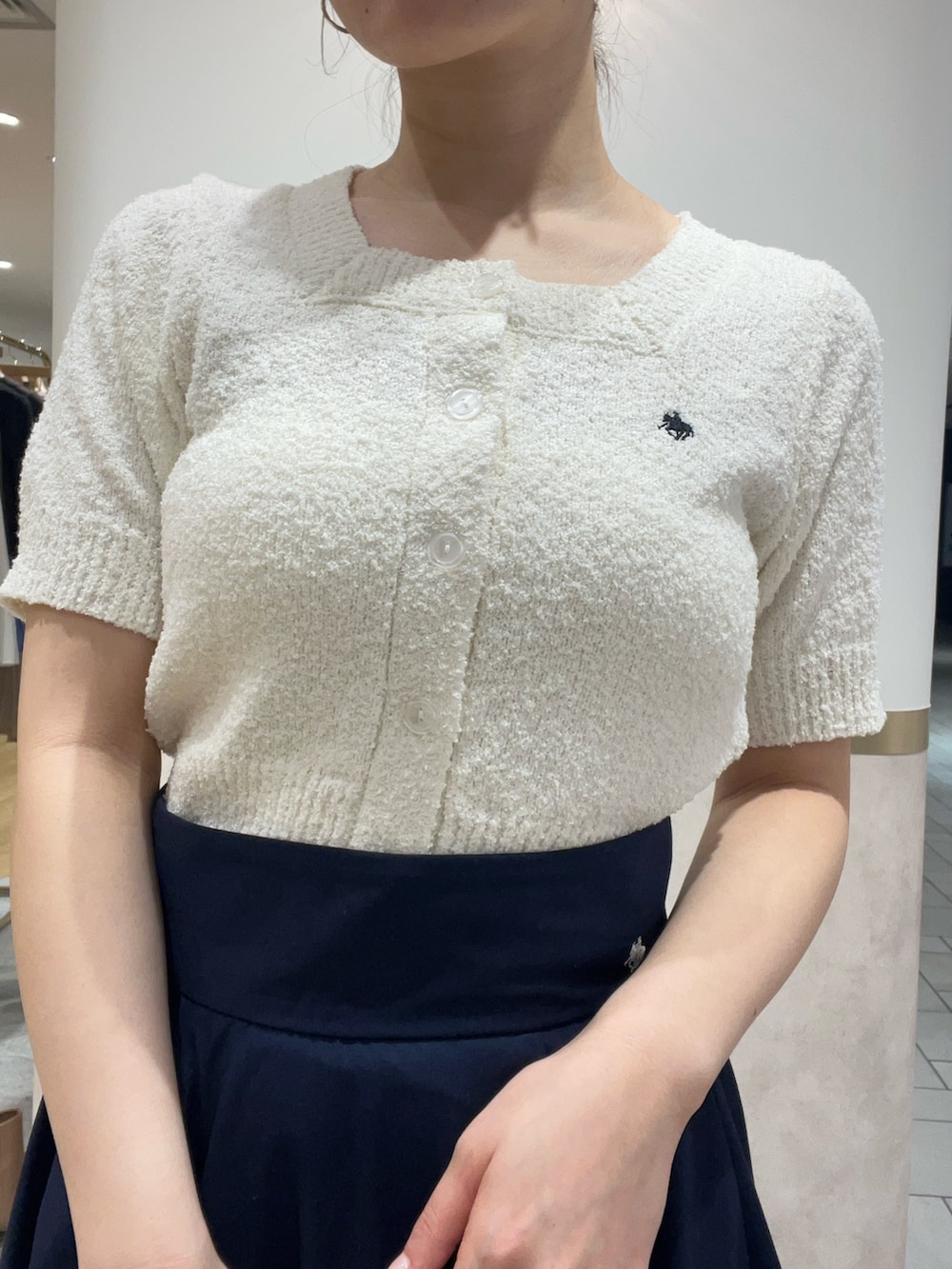 ブルー系のスカート、ホワイト系のニット/セーター、ブラック系のパンプスを着用したレディースの春コーディネートの5枚目の写真