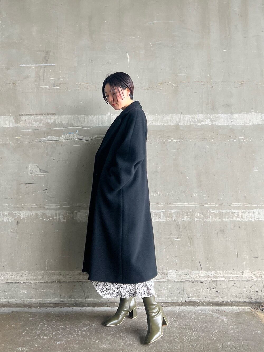 ベージュ系のブーツ、ブラック系のその他アウター、ホワイト系のワンピースを着用したレディースの冬コーディネートの2枚目の写真