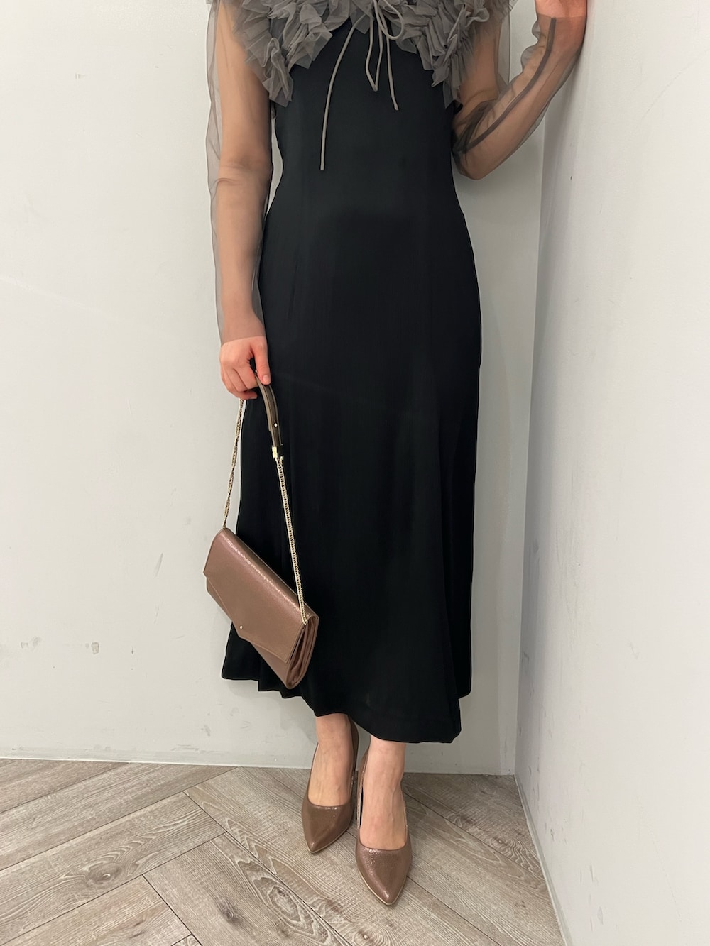 グレー系のドレス、ゴールド系のクラッチバッグ、ゴールド系のパンプスを着用したレディースの春コーディネートの6枚目の写真