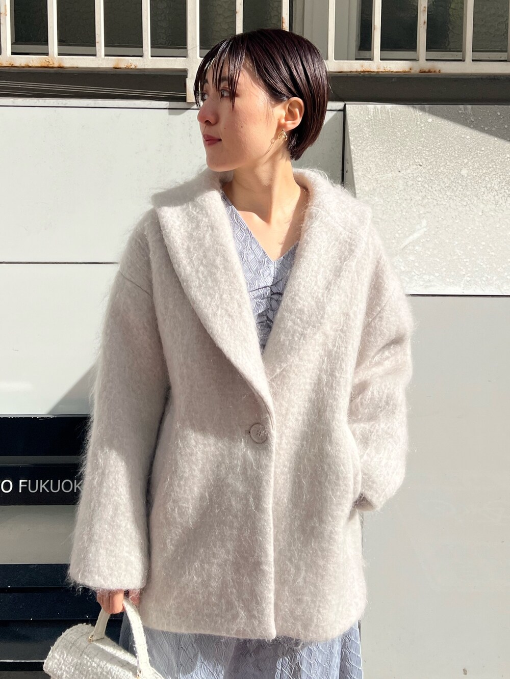 ホワイト系のショルダーバッグ、ベージュ系のブーツ、ベージュ系のその他アウターを着用したレディースの冬コーディネートの4枚目の写真