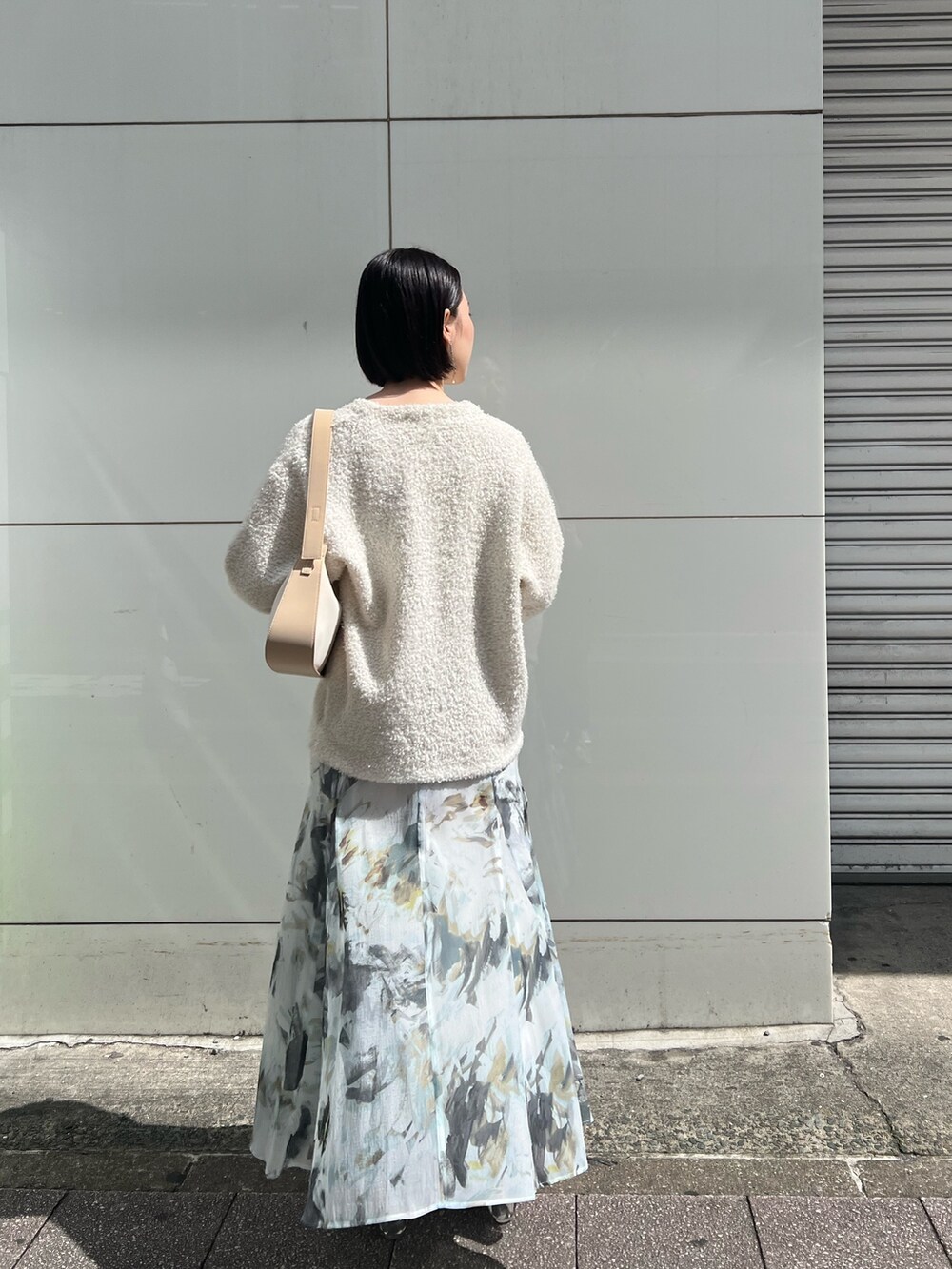 ホワイト系のパンプス、ベージュ系のハンドバッグ、ホワイト系のニット/セーターを着用したレディースの春コーディネートの3枚目の写真