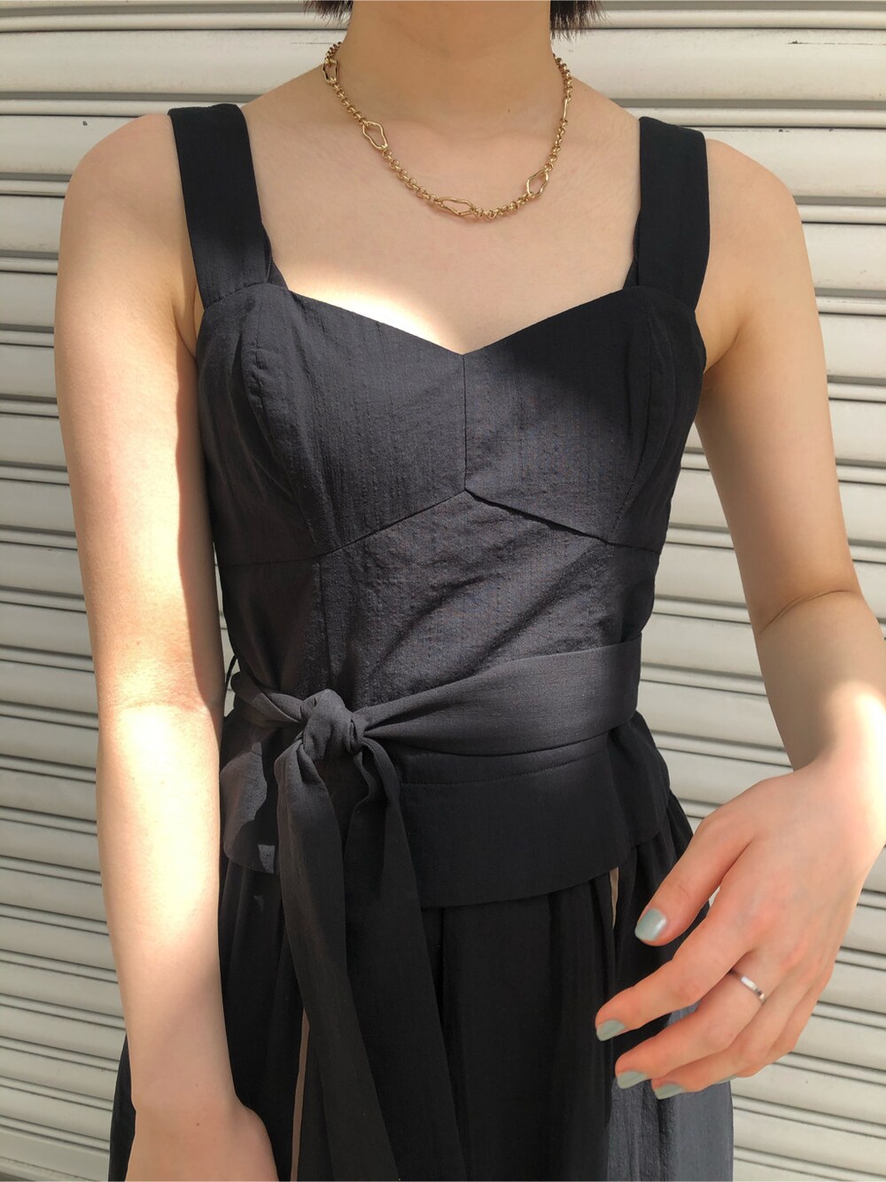 ブラウン系のパンプス、ホワイト系のハンドバッグ、ブラック系のワンピースを着用したレディースの春コーディネートの2枚目の写真