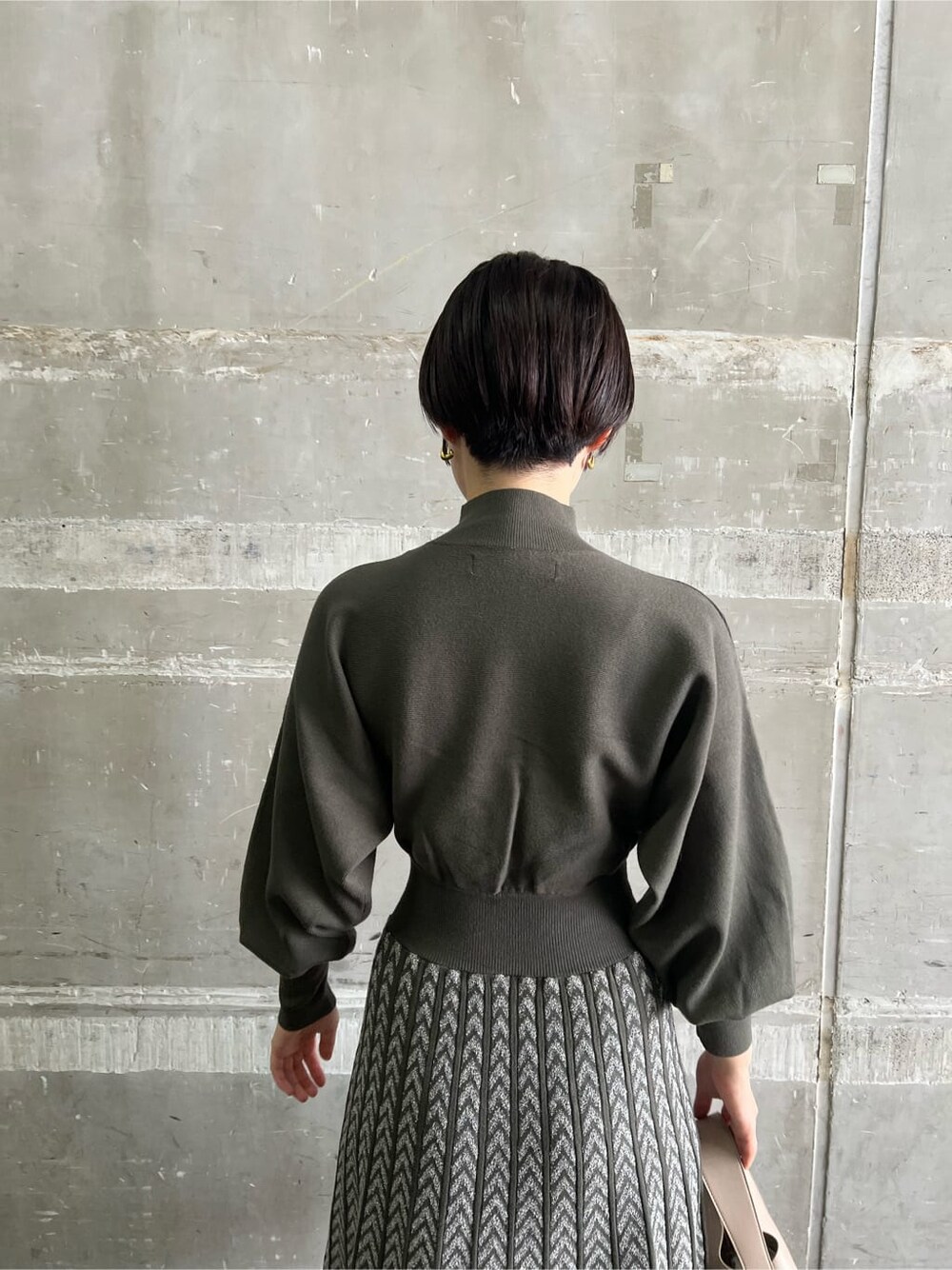 ベージュ系のブーツ、ベージュ系のハンドバッグ、ベージュ系のワンピースを着用したレディースの秋コーディネートの6枚目の写真