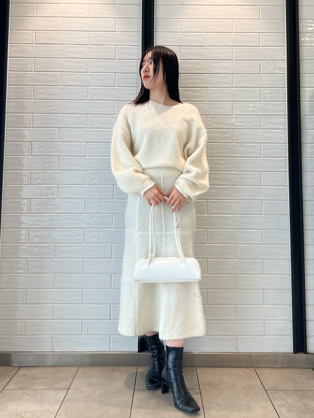 ホワイト系のスカート、ホワイト系のニット/セーター、ホワイト系のショルダーバッグを着用したレディースの秋コーディネートの3枚目の写真