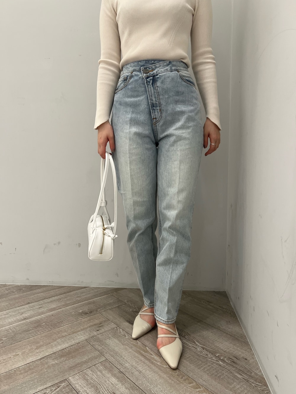 ホワイト系のニット/セーター、ブルー系のデニムパンツ、ホワイト系のパンプスを着用したレディースの春コーディネートの4枚目の写真