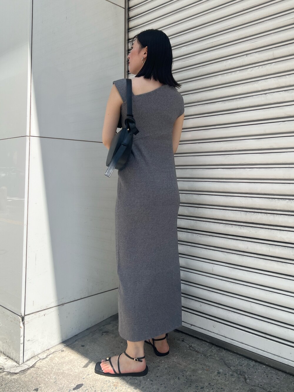 グレー系のワンピース、ブラック系のサンダル、ブラック系のショルダーバッグを着用したレディースの夏コーディネートの2枚目の写真