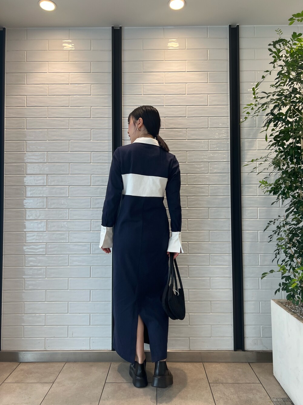 ブラック系のハンドバッグ、ブラック系のブーツ、ブルー系のワンピースを着用したレディースの秋コーディネートの3枚目の写真