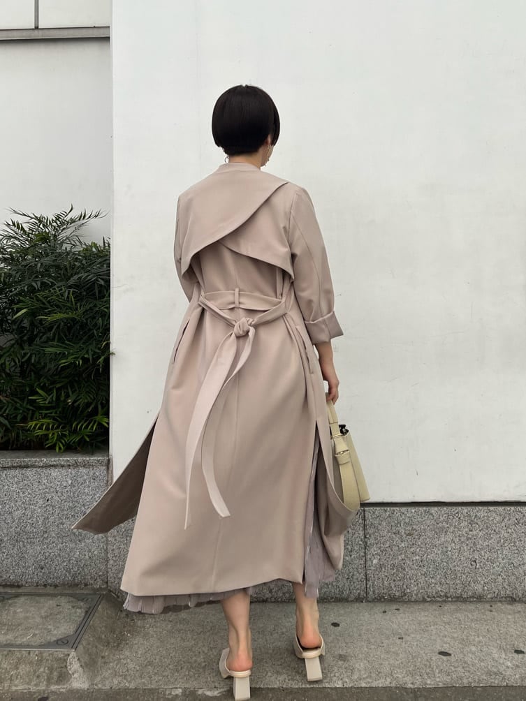 ホワイト系のノーカラーコート、グレー系のワンピース、ホワイト系のサンダルを着用したレディースの冬コーディネートの8枚目の写真