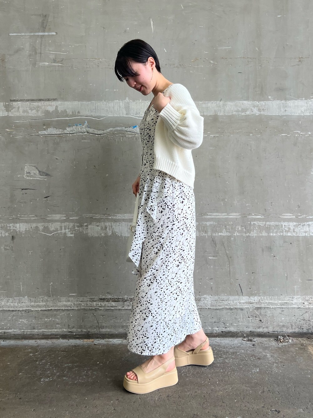 ホワイト系のワンピース、ホワイト系のカーディガン/ボレロ、ベージュ系のサンダルを着用したレディースの春コーディネートの2枚目の写真