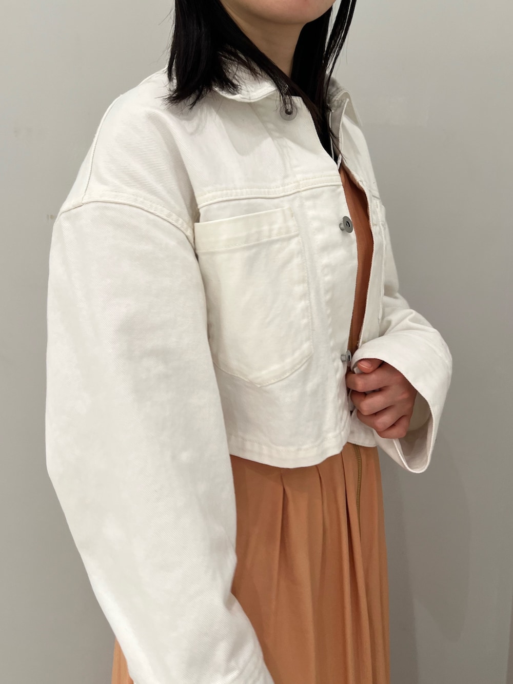 ホワイト系のサンダル、オレンジ系のワンピース、ホワイト系のデニムジャケットを着用したレディースの春コーディネートの4枚目の写真