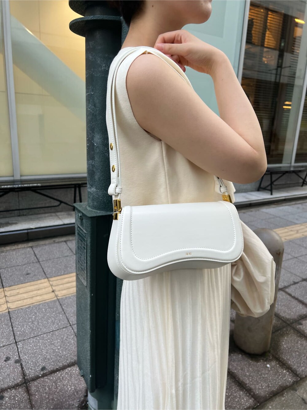 ホワイト系のワンピース、ホワイト系のショルダーバッグ、ゴールド系のピアス（両耳用）を着用したレディースの夏コーディネートの5枚目の写真