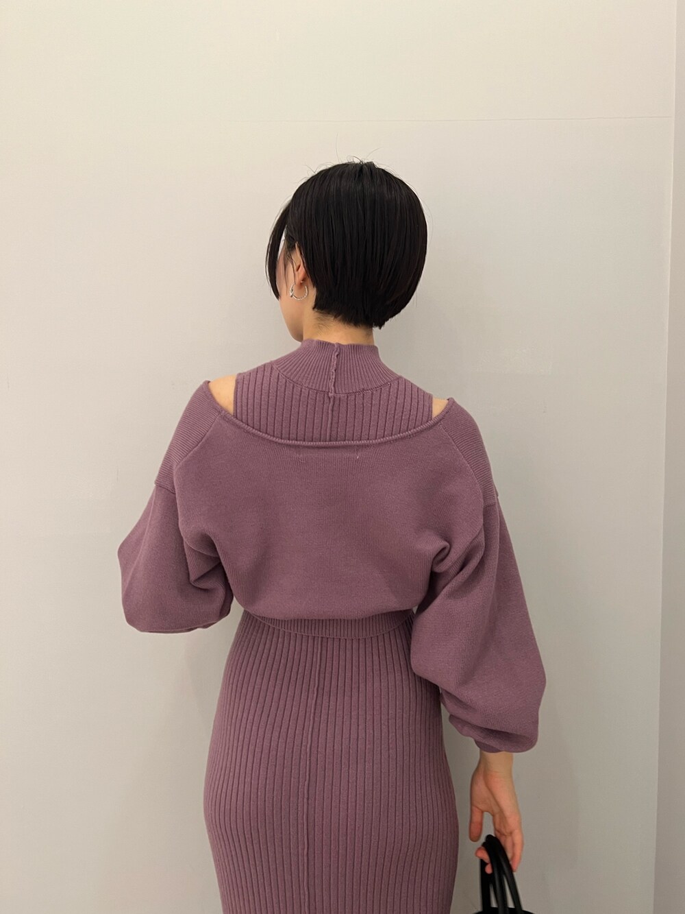 レッド系のブーツ、ブラック系のハンドバッグ、パープル系のワンピースを着用したレディースの冬コーディネートの5枚目の写真