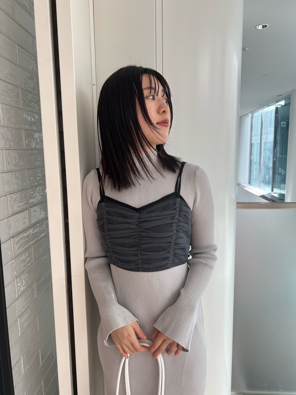 ブラック系のステンカラーコート、ブルー系のワンピース、ブラック系のブーツを着用したレディースの冬コーディネートの6枚目の写真